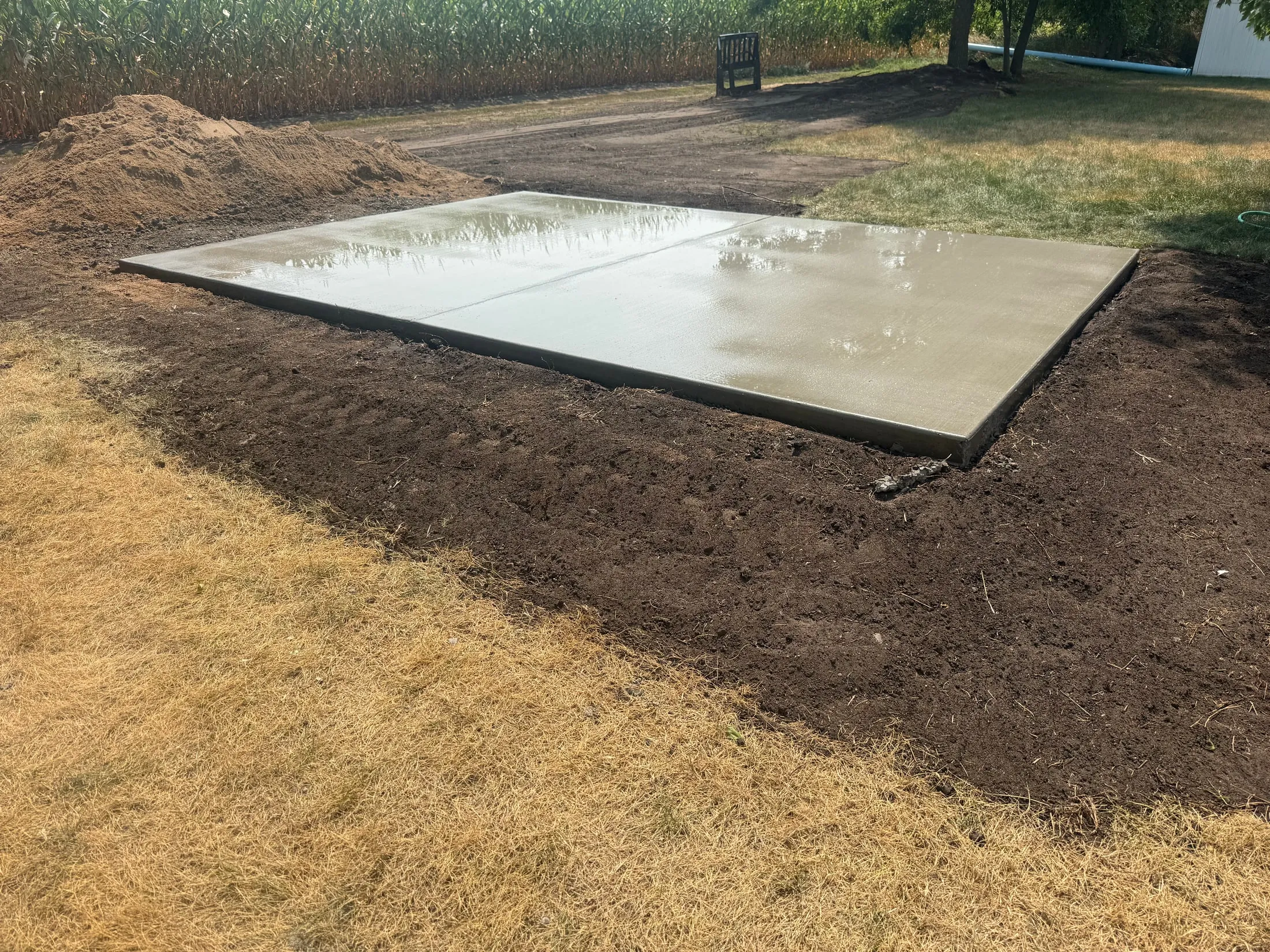 Fresh concrete slab with surrounding soil and grading.