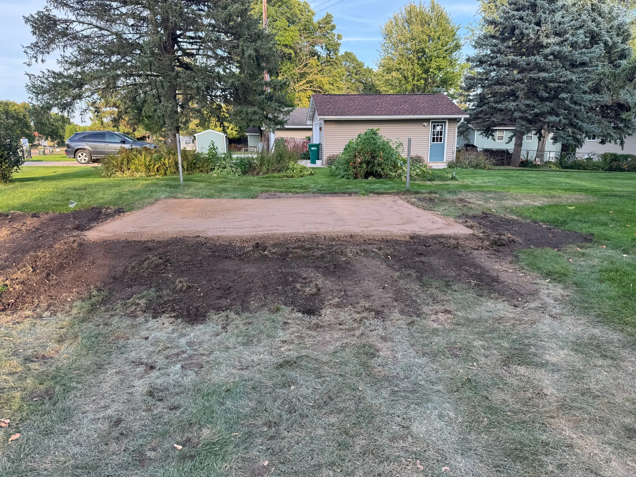 Rectangular gravel pad with newly graded soil around the edge.