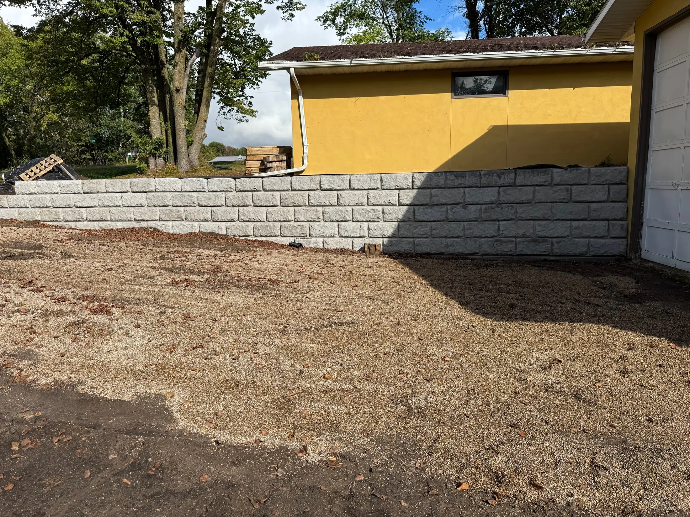 Split-face block retaining wall along a garage with regraded base.