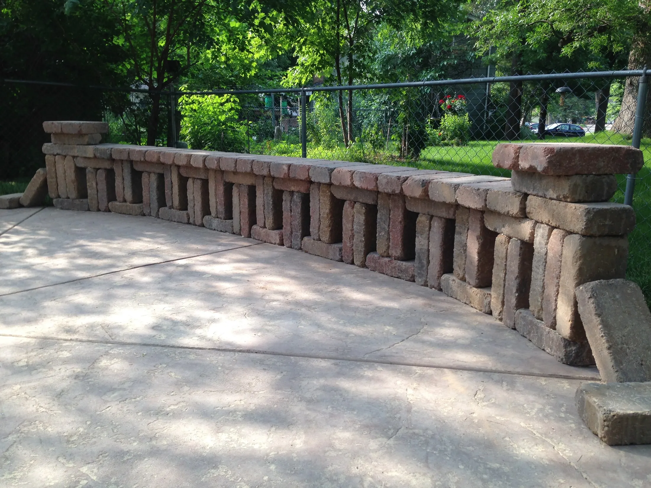 Decorative open-pattern block retaining wall bordering a stamped concrete patio.
