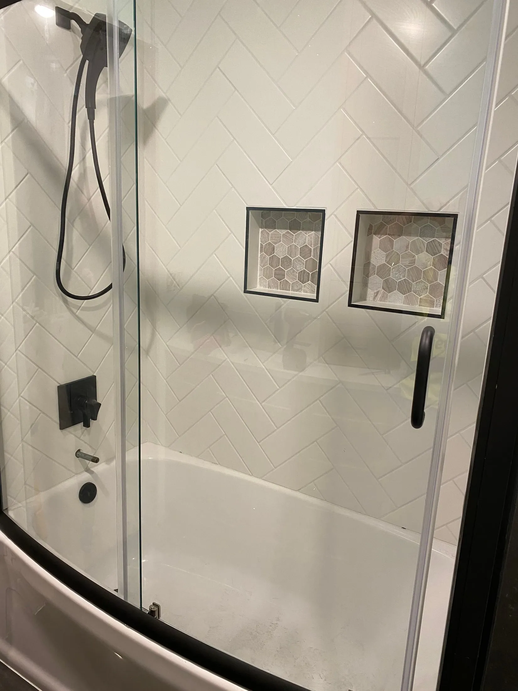 Herringbone tub/shower with two inset niches and black hardware.