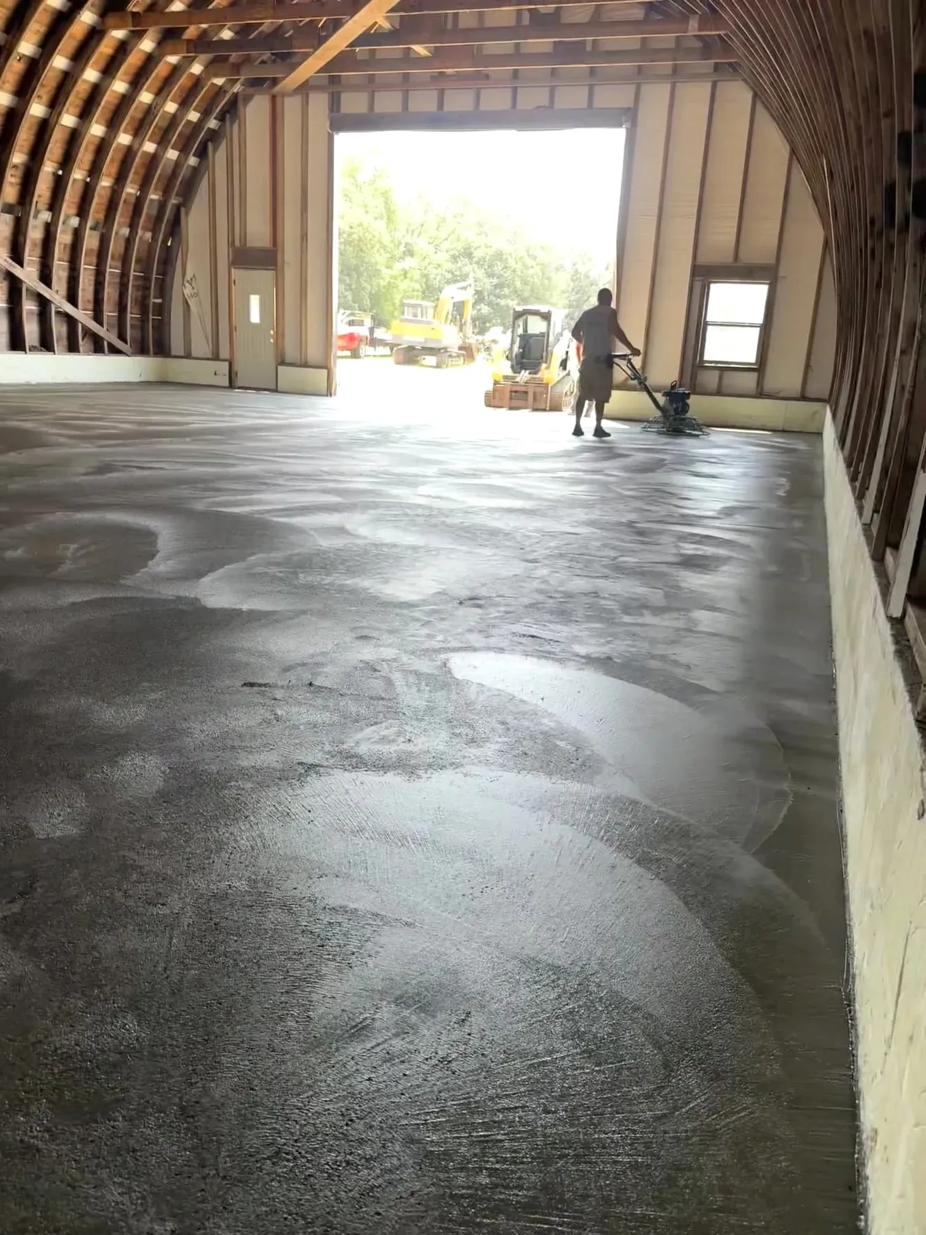 Concrete finishing inside an arched Quonset building, July 2026.