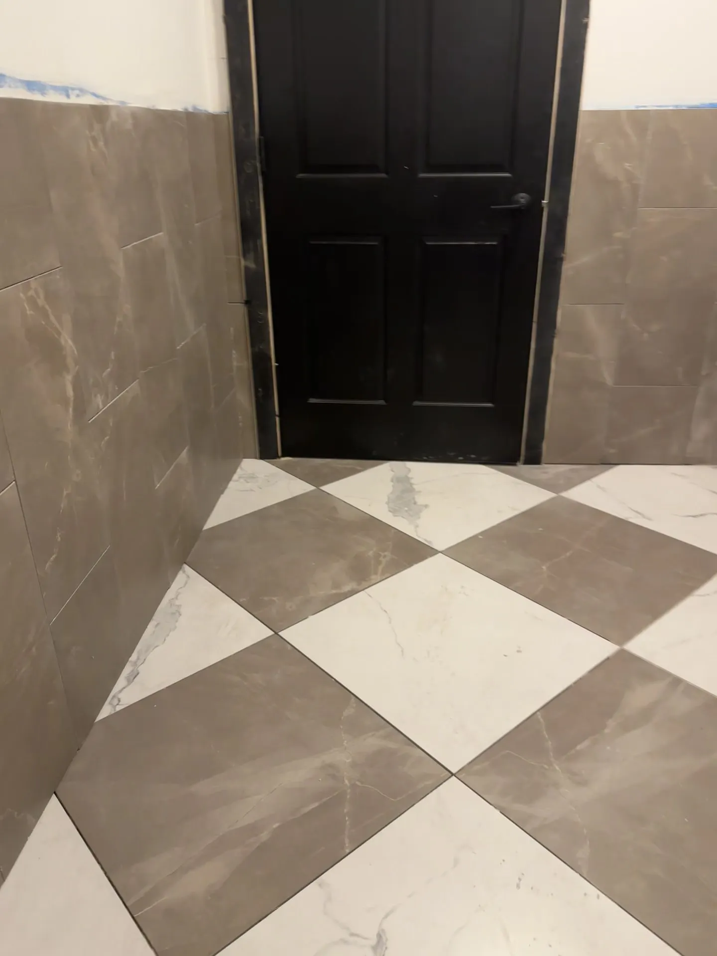 Checkerboard tile floor meeting coordinated wall tile at Tannin & Oak.