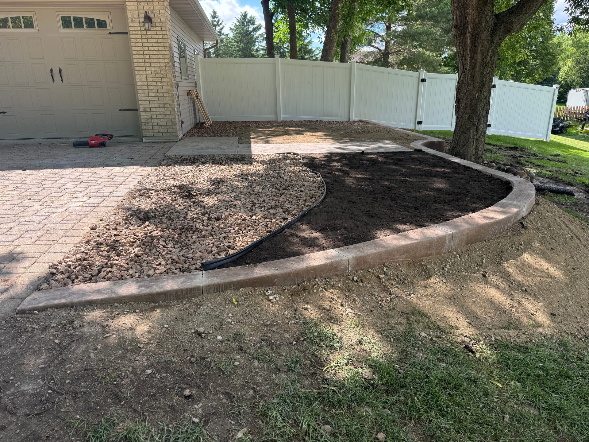 Curved concrete curbing with decorative rock landscape border and edging fabric in west-central Minnesota.
