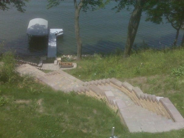 Completed concrete boat launch ramp leading to waterfront with metal canopy structure.