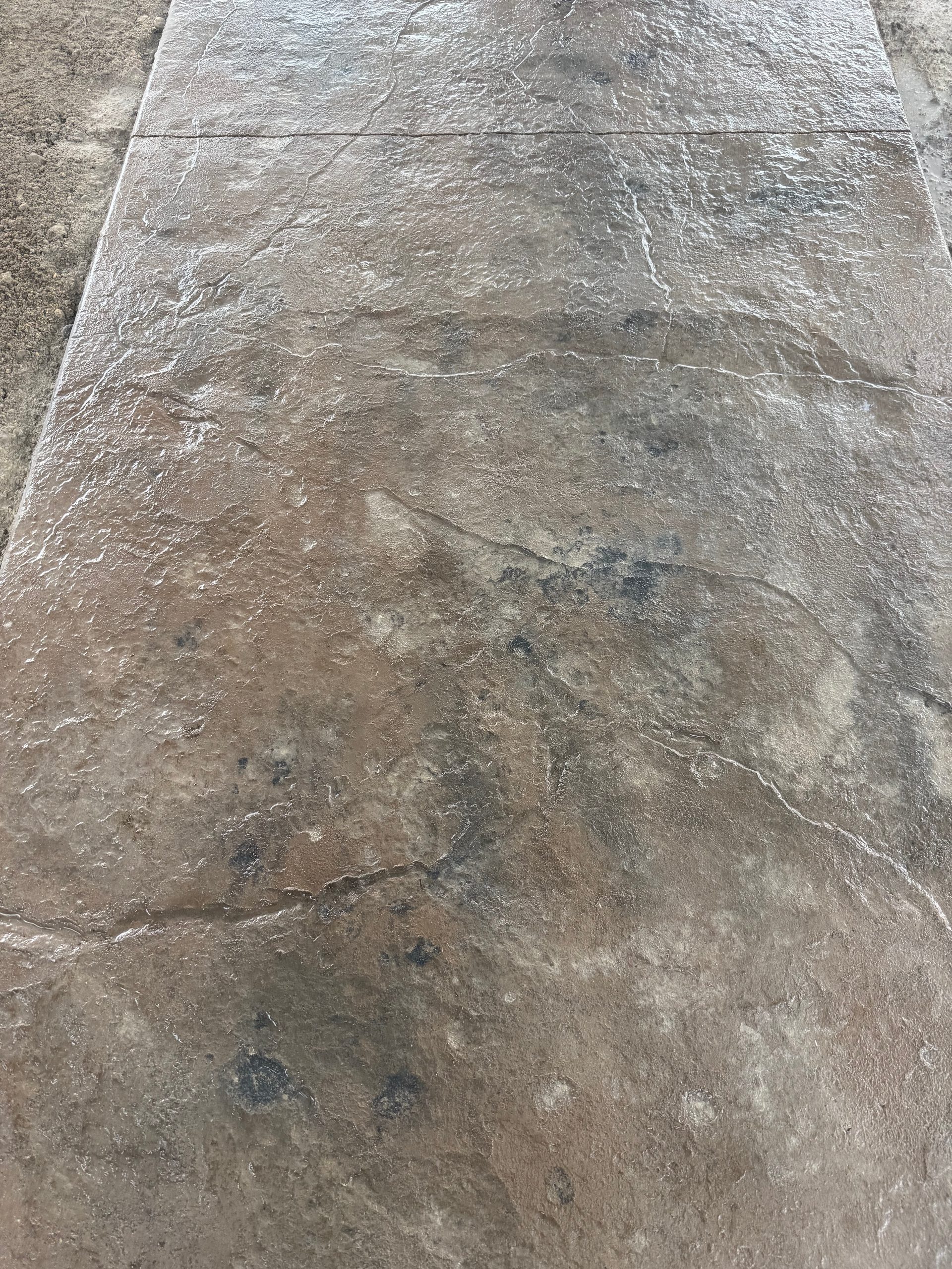 Freshly stamped concrete patio slab with stone-pattern finish and expansion joint in west-central Minnesota.