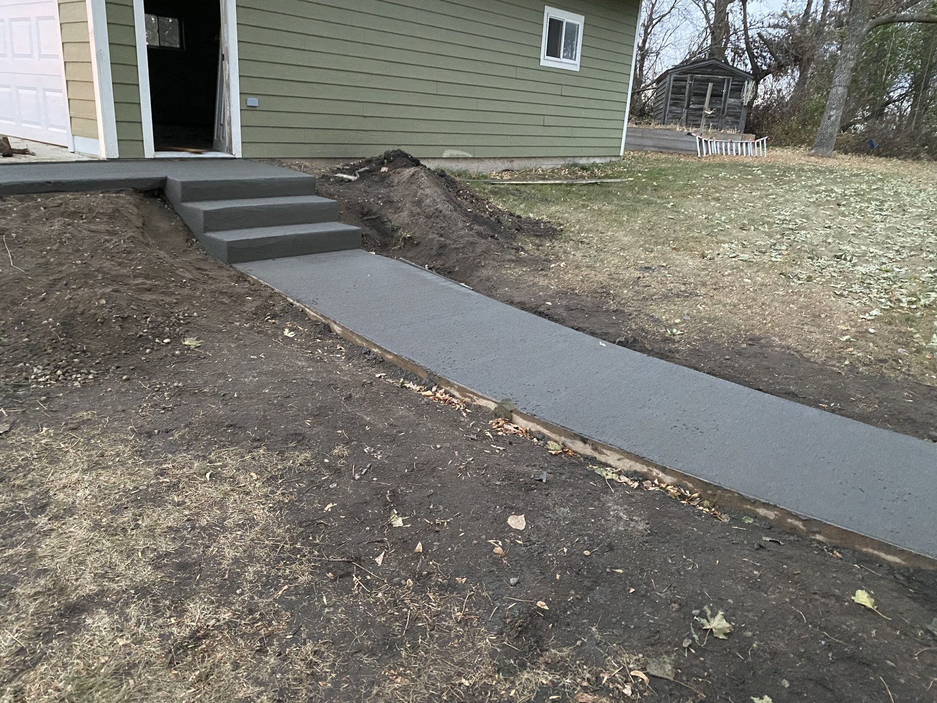 Newly installed concrete walkway and entry steps leading to residential home entrance.