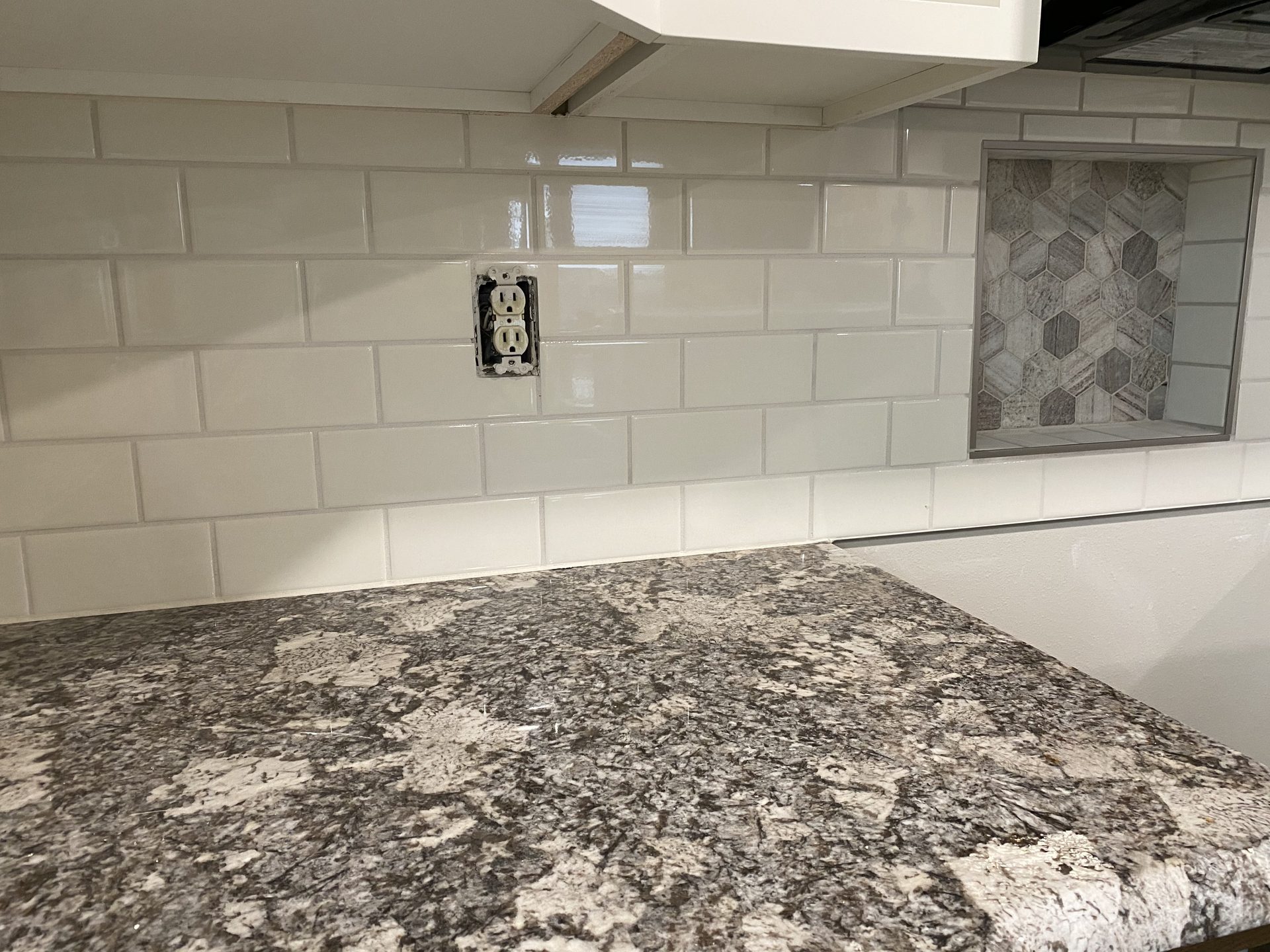 Completed kitchen backsplash with cream subway tile and granite countertop installation
