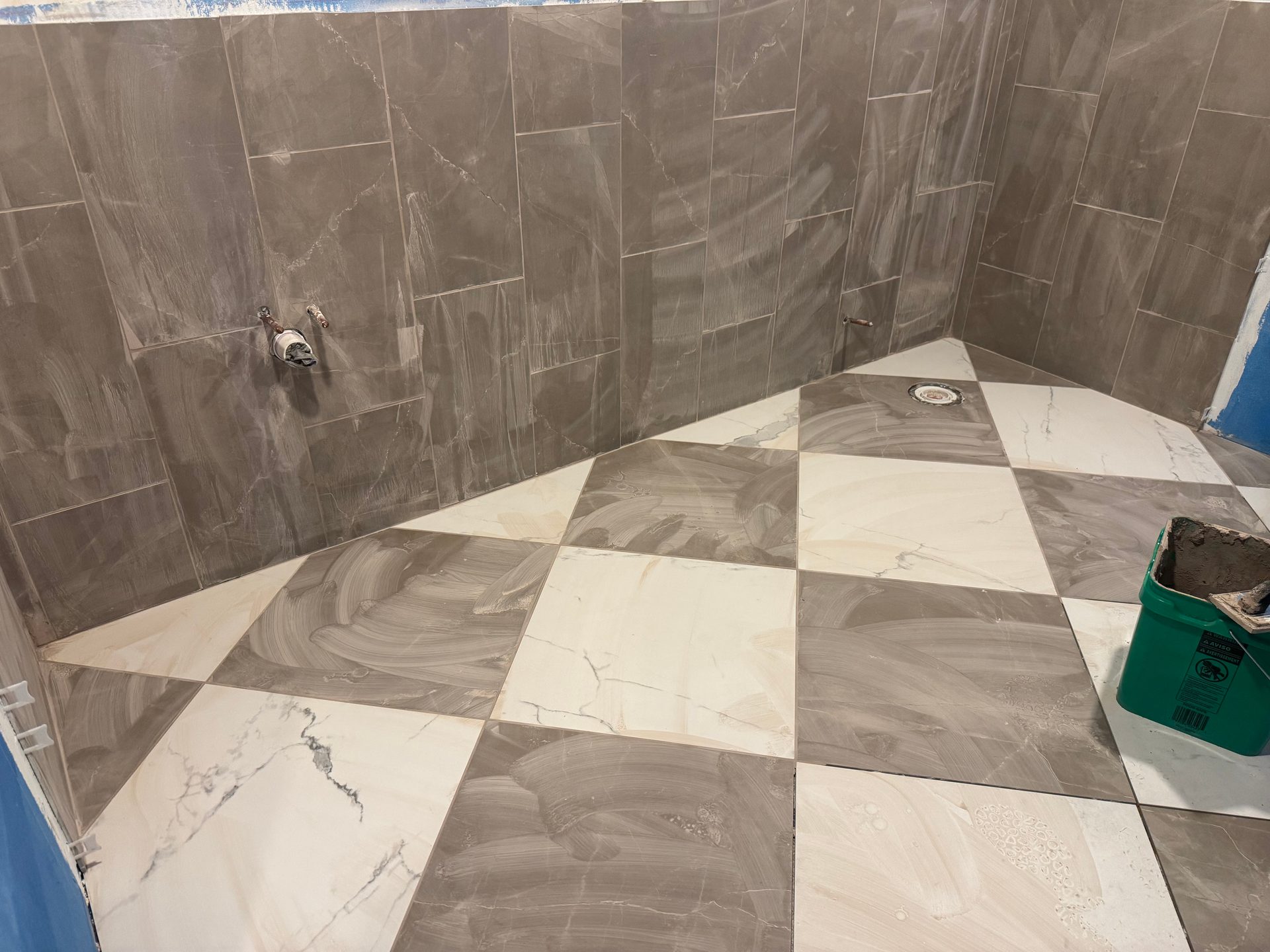 Tile shower installation in progress with large-format wall tile and diagonal checkerboard floor pattern in west-central Minnesota.